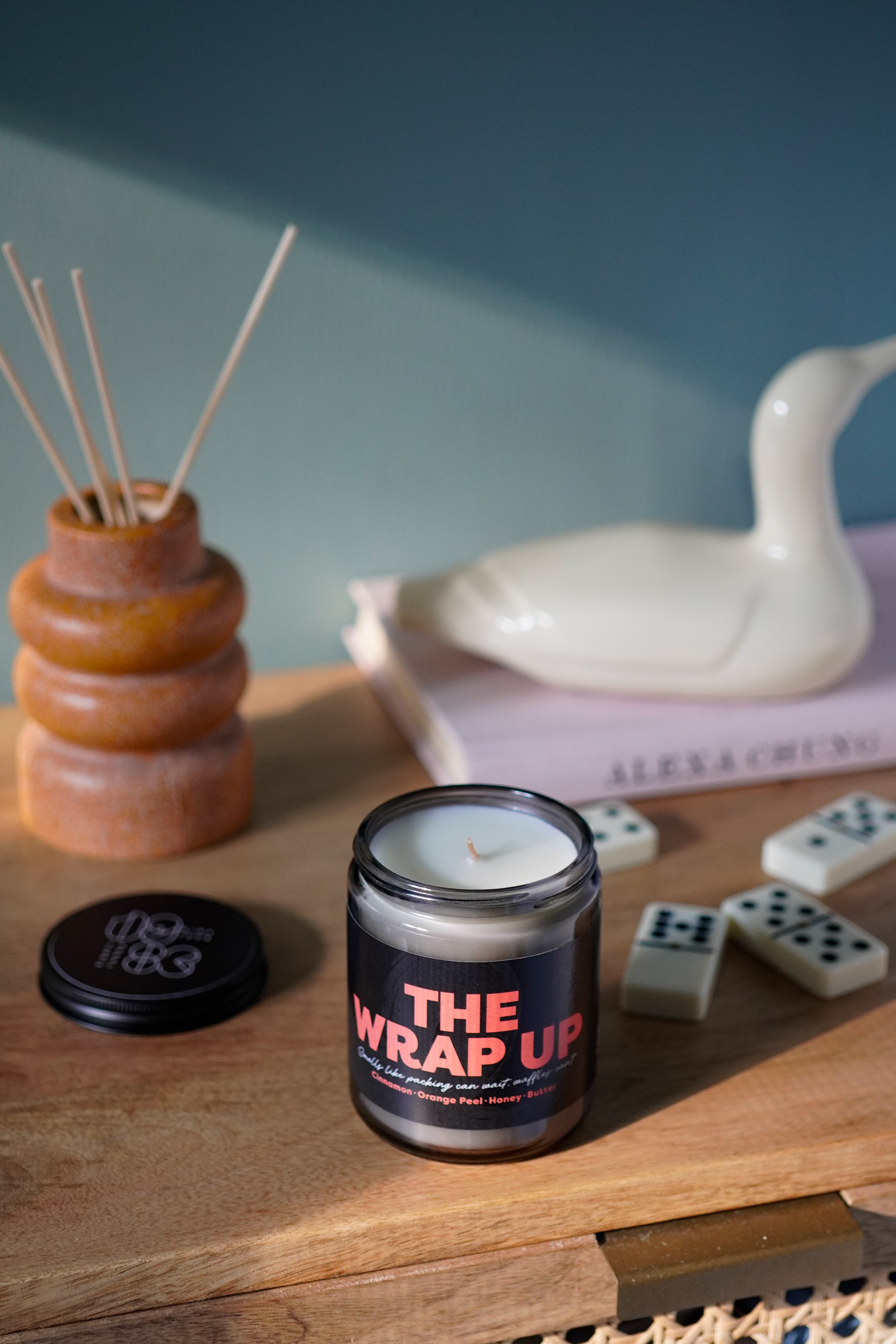 The Wrap Up candle by 1983 on a wooden table, hand-poured vegan candle with cinnamon, orange peel, honey and butter notes.